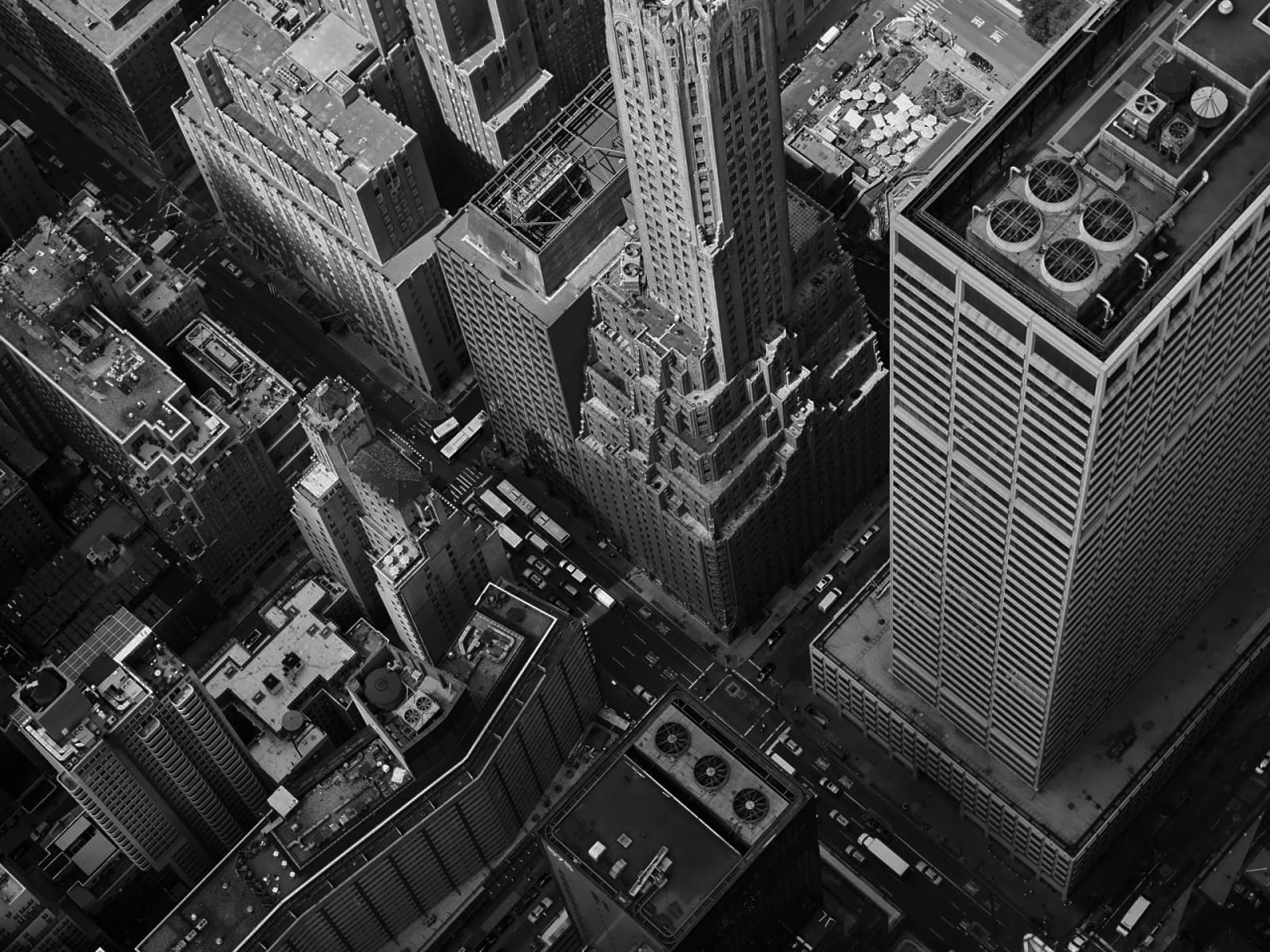 Black and white aerial view of a city intersection with tall buildings and busy streets.