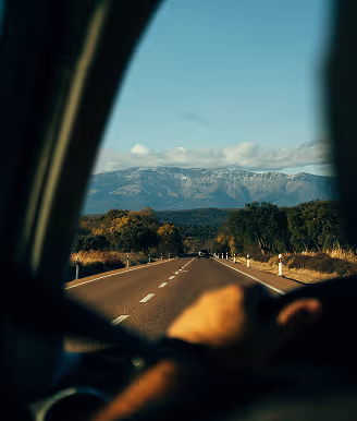 Road leading towards mountains, seen from inside a car.