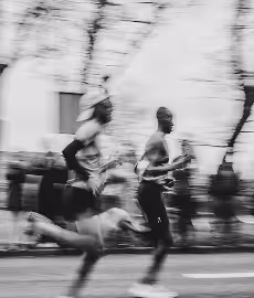 Blurred black and white photo of two runners in a race.