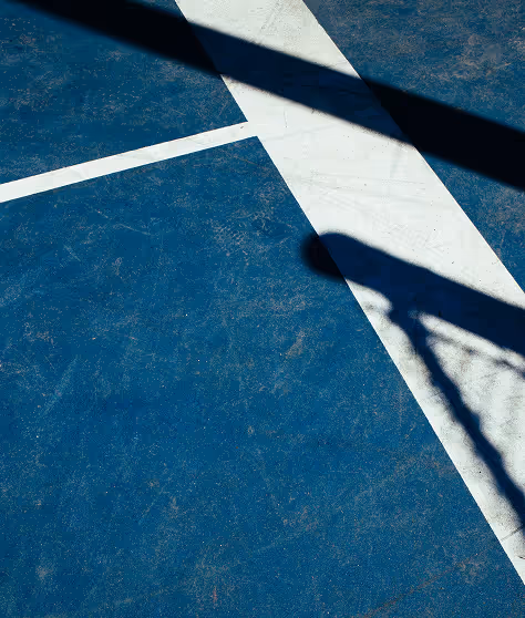 Shadow of a basketball hoop on a blue court.